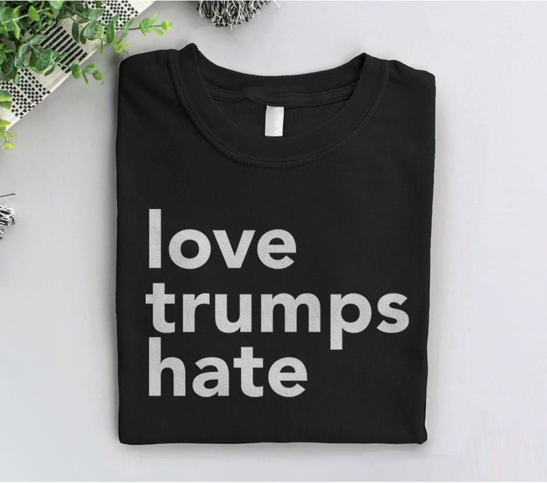 Puede incluir: Camiseta negra con texto blanco que dice "love trumps hate".
