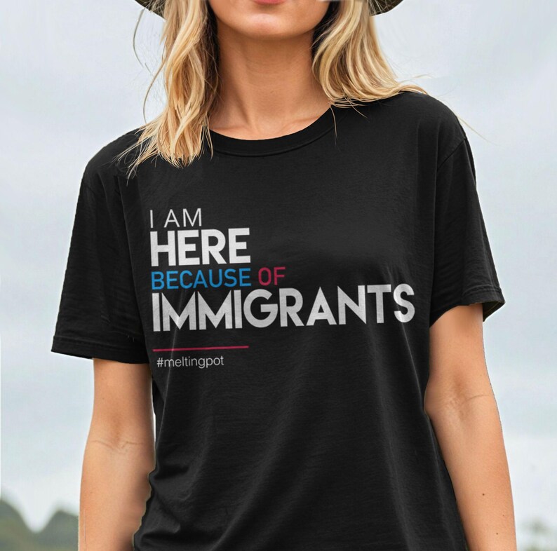 May include: Black t-shirt with white text that reads "I am here because of immigrants #meltingpot".