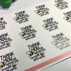 May include: A sheet of round stickers with a white background and black text that says "Thank You for Supporting Small Bees-ness". Each sticker features a cartoon bee with black and yellow stripes.