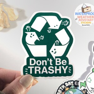 Op de afbeelding: Groene en witte sticker met een recycle-symbool en de tekst "Don't Be TRASHY".