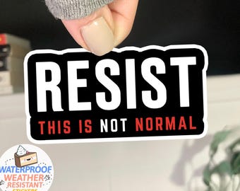 May include: Black and white sticker with the text "RESIST THIS IS NOT NORMAL" in white letters on a black background. The text "THIS IS NOT NORMAL" is in red letters.