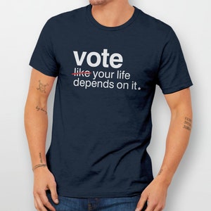 May include: A navy blue t-shirt with white text that reads "vote like your life depends on it*"