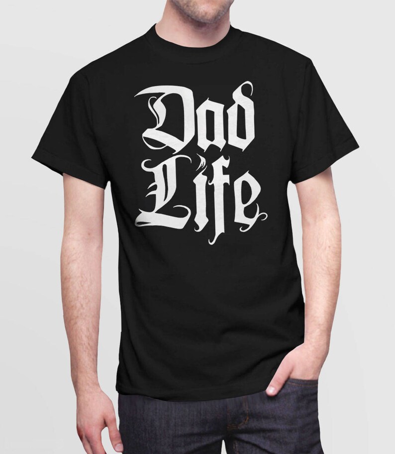 Puede incluir: Camiseta negra con texto blanco que dice "Dad Life" en una fuente estilizada.
