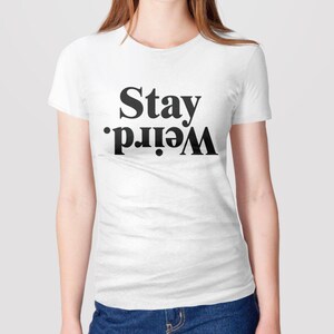 Puede incluir: Camiseta blanca con texto negro que dice "Stay Weird."