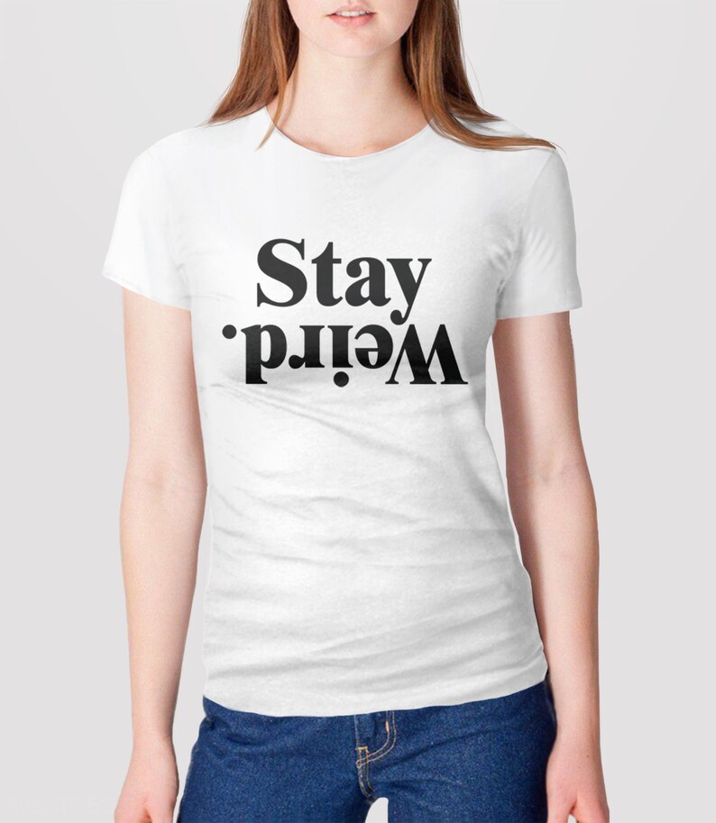 Puede incluir: Camiseta blanca con texto negro que dice "Stay Weird."
