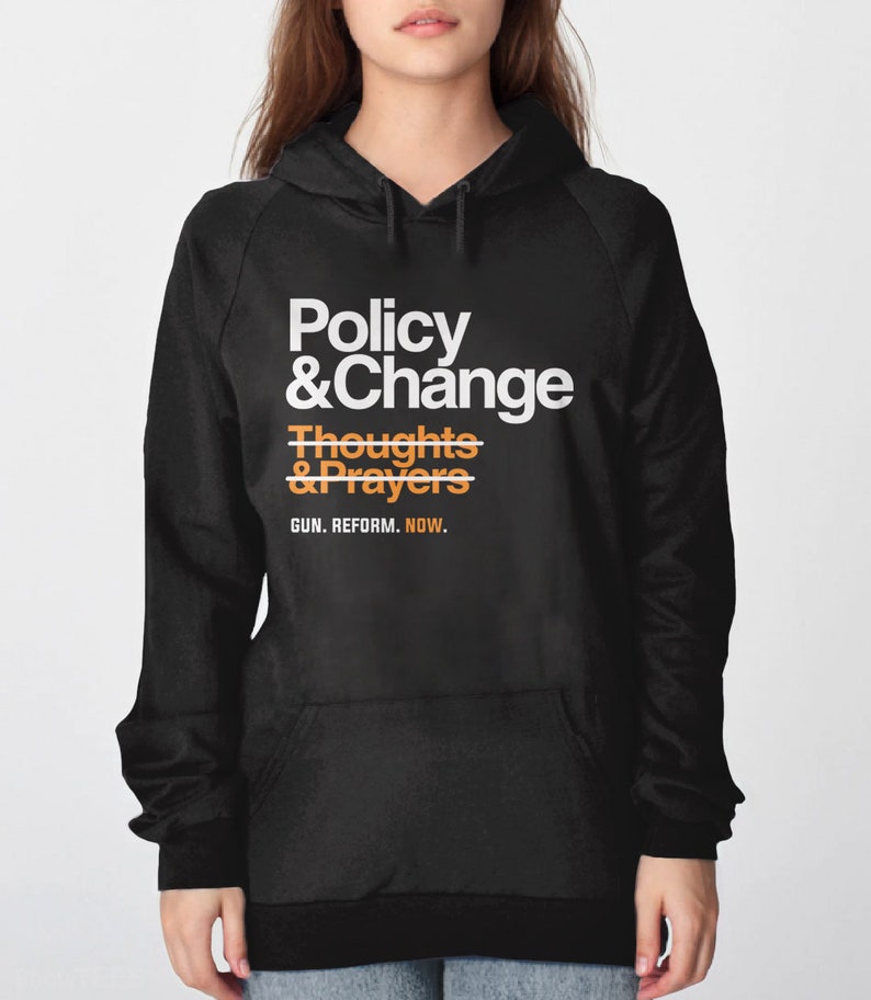 May include: Black hooded sweatshirt with white text that reads "Policy & Change" and orange text that reads "Thoughts & Prayers" with a line through it. The text "GUN. REFORM. NOW." is printed below in white.