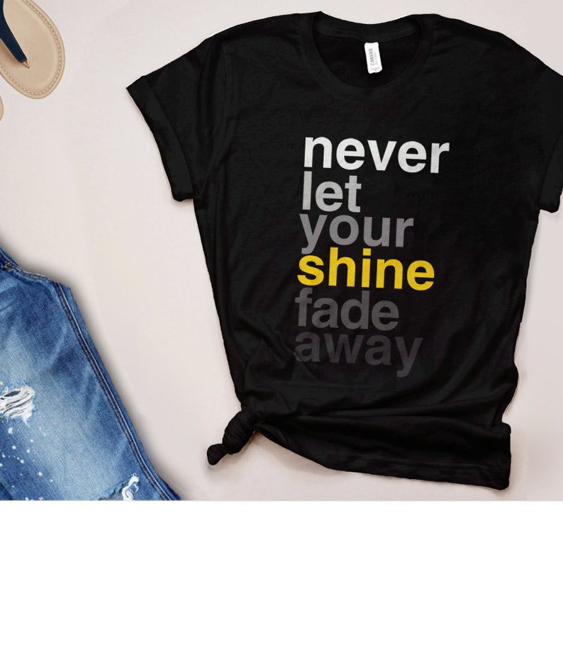 May include: Black t-shirt with the text "never let your shine fade away" in gray and yellow lettering.