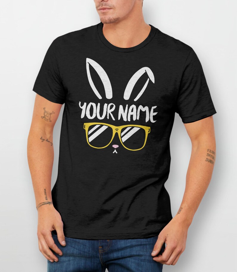 May include: Black t-shirt with a white bunny rabbit graphic wearing yellow sunglasses. The text "YOUR NAME" is printed on the shirt.