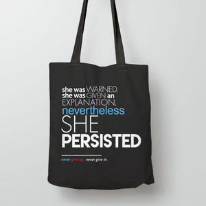 May include: Black tote bag with the text "she was WARNED. she was GIVEN an EXPLANATION. nevertheless SHE PERSISTED" in white and blue. The bottom of the bag reads "never give up. never give in."