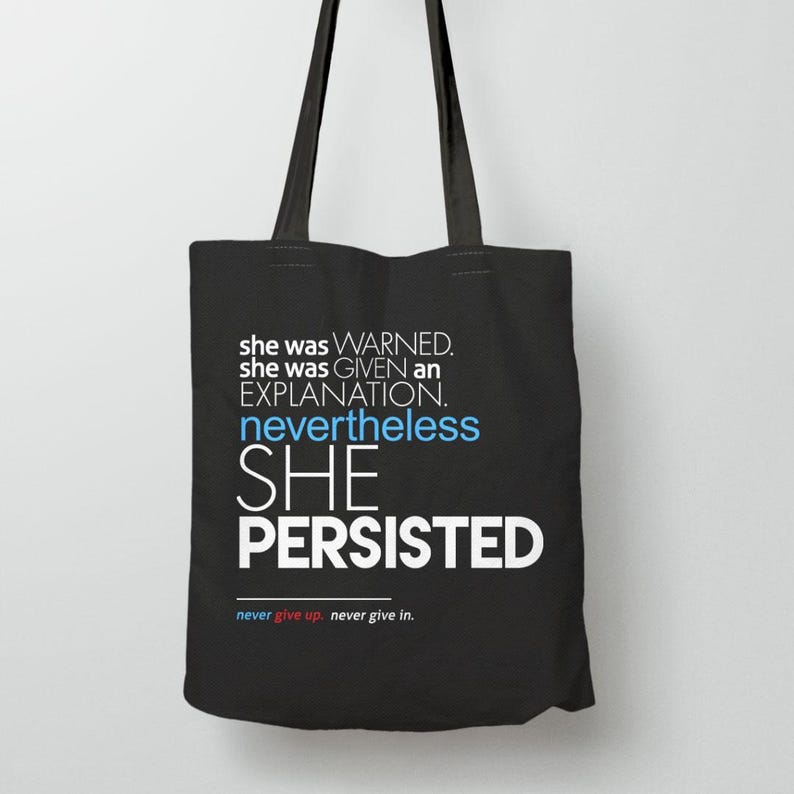 May include: Black tote bag with the text "she was WARNED. she was GIVEN an EXPLANATION. nevertheless SHE PERSISTED" in white and blue. The bottom of the bag reads "never give up. never give in."