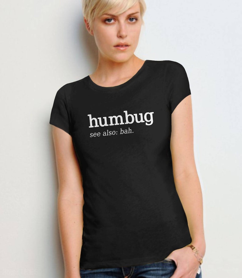 K&ouml;nnte beinhalten: Schwarzes T-Shirt mit dem Wort "humbug" in Wei&szlig;, darunter "see also: bah." gedruckt. Das T-Shirt hat einen Rundhalsausschnitt.