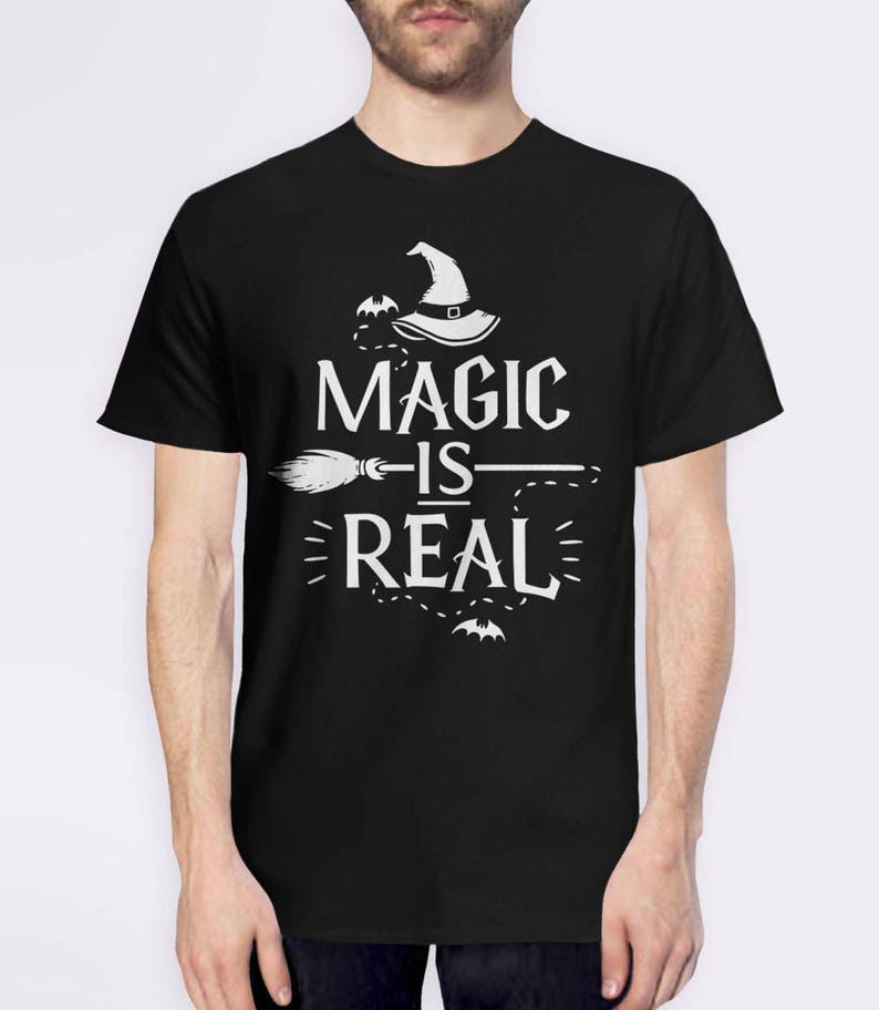 May include: Black t-shirt with a white graphic design featuring a witch's hat, a broom, and the text "Magic is Real".