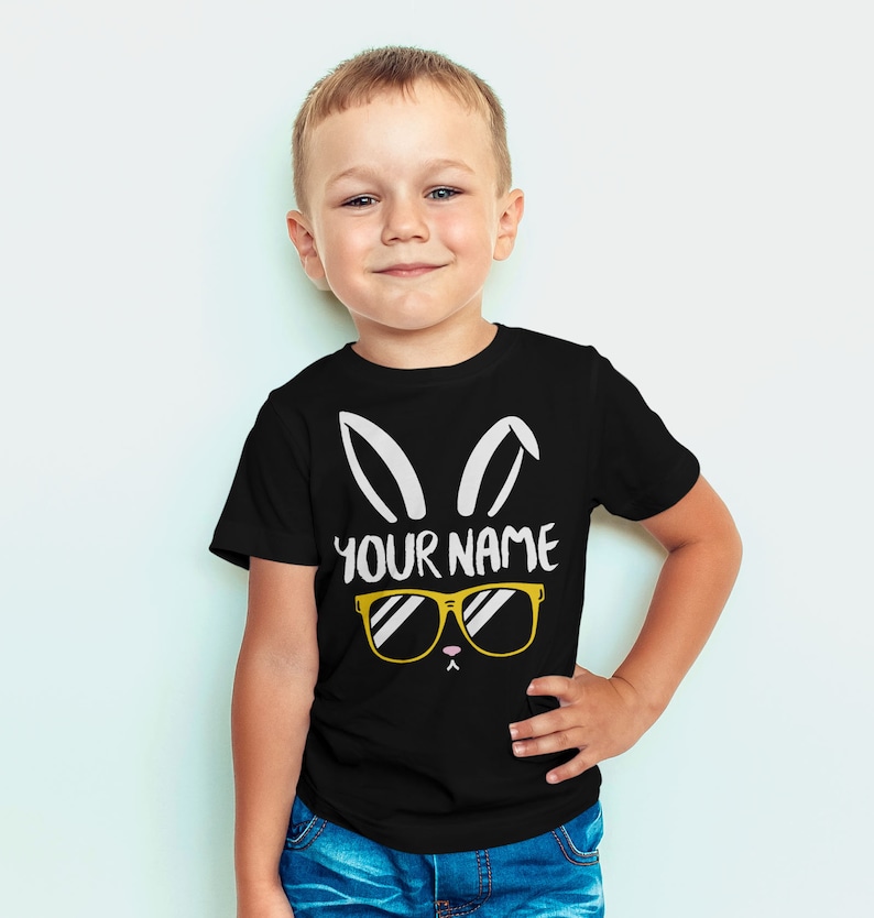 May include: A black t-shirt with a white bunny rabbit graphic wearing sunglasses. The text "YOUR NAME" is printed below the graphic.