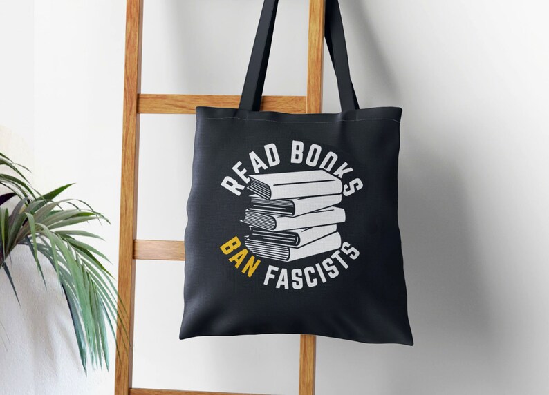 a book bag hanging on a ladder with read books, ban fascists text