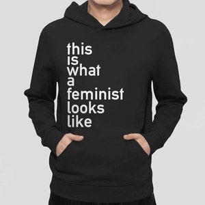 Pu&ograve; includere: Felpa con cappuccio nera con il testo "this is what a feminist looks like" in bianco.