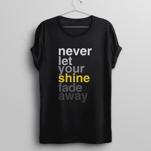 May include: Black t-shirt with the text "never let your shine fade away" in white and gray lettering. The word "shine" is in yellow.