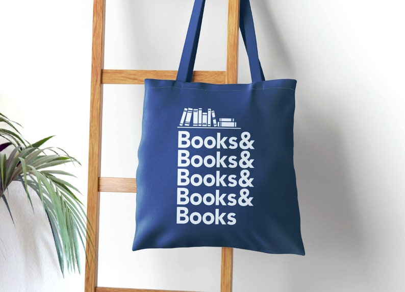 Books and Books Helvetica text with bookshelf graphic on a royal blue canvas tote bag