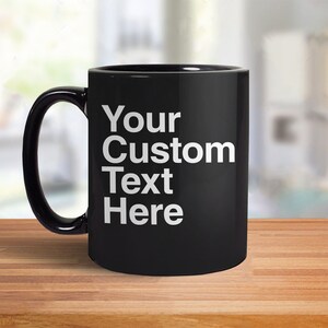 May include: Black ceramic coffee mug with a white inscription that reads "Your Custom Text Here".