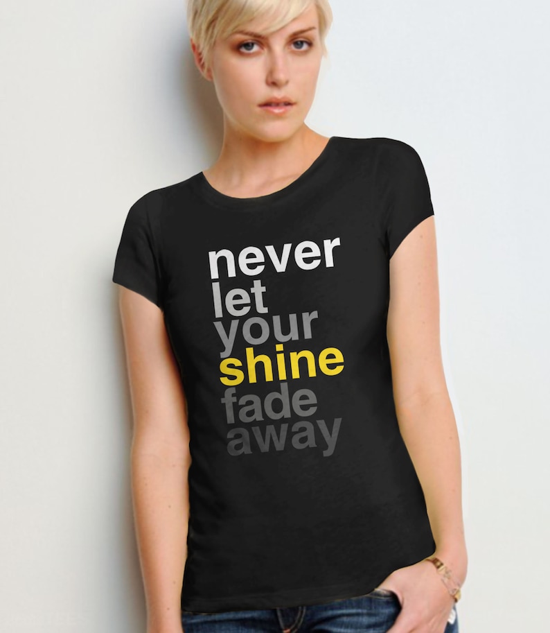 May include: Black t-shirt with the text "never let your shine fade away" in white and yellow lettering.