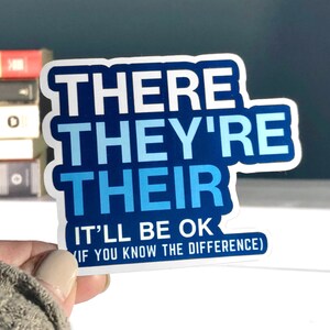 May include: A white sticker with blue text that reads "THERE THEY'RE THEIR IT'LL BE OK (IF YOU KNOW THE DIFFERENCE)".
