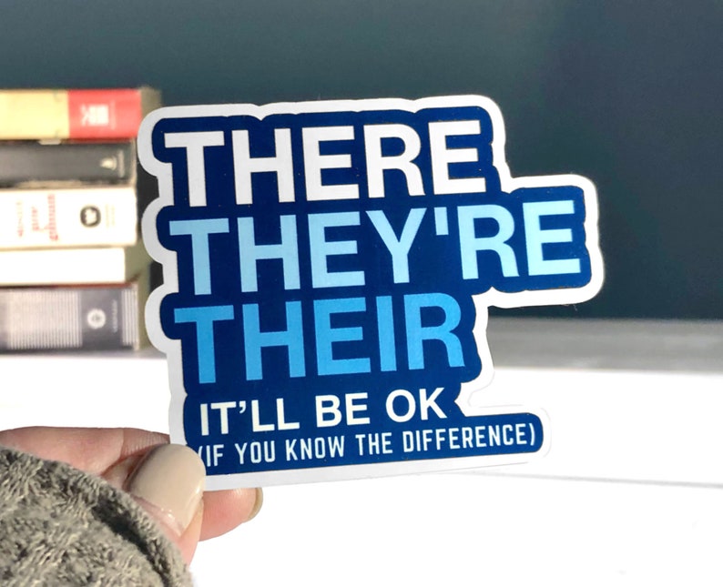 May include: A white sticker with blue text that reads "THERE THEY'RE THEIR IT'LL BE OK (IF YOU KNOW THE DIFFERENCE)".