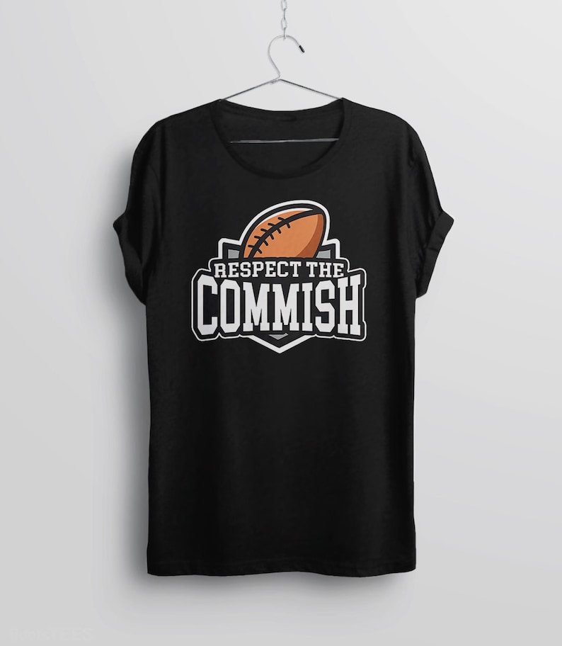 May include: Black t-shirt with a white graphic of a football and the text "Respect the Commish".