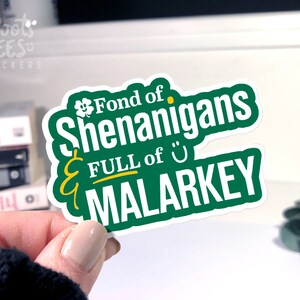 Puede incluir: Pegatina verde y blanca con el texto "Fond of Shenanigans & FULL of MALARKEY" con un tr&eacute;bol y una carita sonriente.