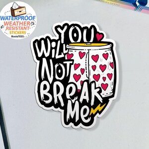 May include: A white sticker with the words "YOU WILL NOT BREAK ME" in a bold, black font. The design includes a jar filled with red hearts and a yellow lightning bolt. A smaller sticker in the upper left corner says "WATERPROOF WEATHER RESISTANT STICKERS".