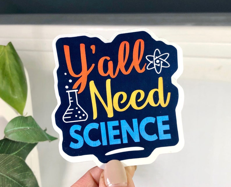 K&ouml;nnte beinhalten: Ein Aufkleber mit dem Text "Y'all Need Science" in einer bunten Schriftart. Der Aufkleber hat einen blauen Hintergrund mit einem wei&szlig;en Atomsymbol und einem Becherglas mit gelber Fl&uuml;ssigkeit.