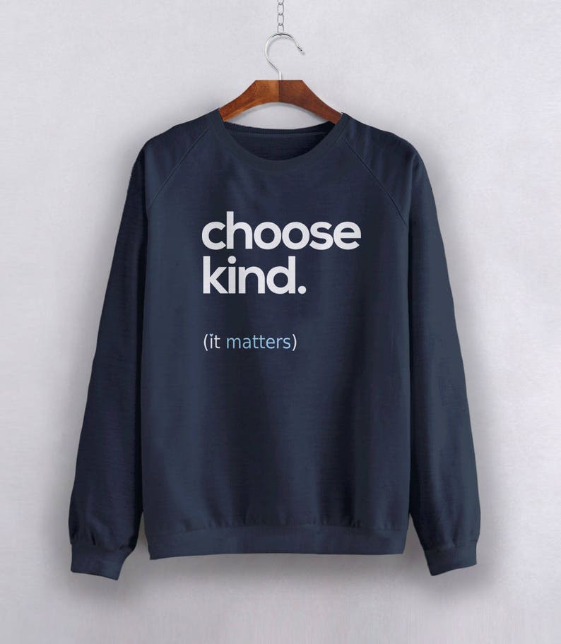以下が含まれることがあります： 白で「choose kind. (it matters)」とプリントされたネイビーブルーのスウェットシャツ