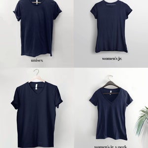 Pode incluir: Quatro camisetas azul-marinho penduradas em cabides contra um fundo branco. As camisetas s&atilde;o exibidas em quatro estilos diferentes: unissex, j&uacute;nior feminino, gola em V unissex e gola em V j&uacute;nior feminino. O texto "Style Guide" &eacute; exibido na parte inferior da imagem.