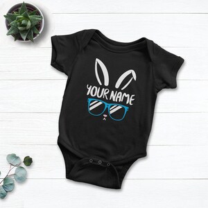May include: Black baby onesie with a white bunny face wearing blue sunglasses and the text "YOUR NAME".
