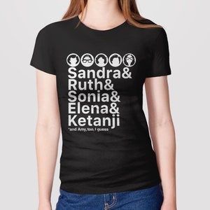 May include: Black t-shirt with white text and illustrations of five women. The text reads "Sandra & Ruth & Sonia & Elena & Ketanji *and Amy, too, I guess".