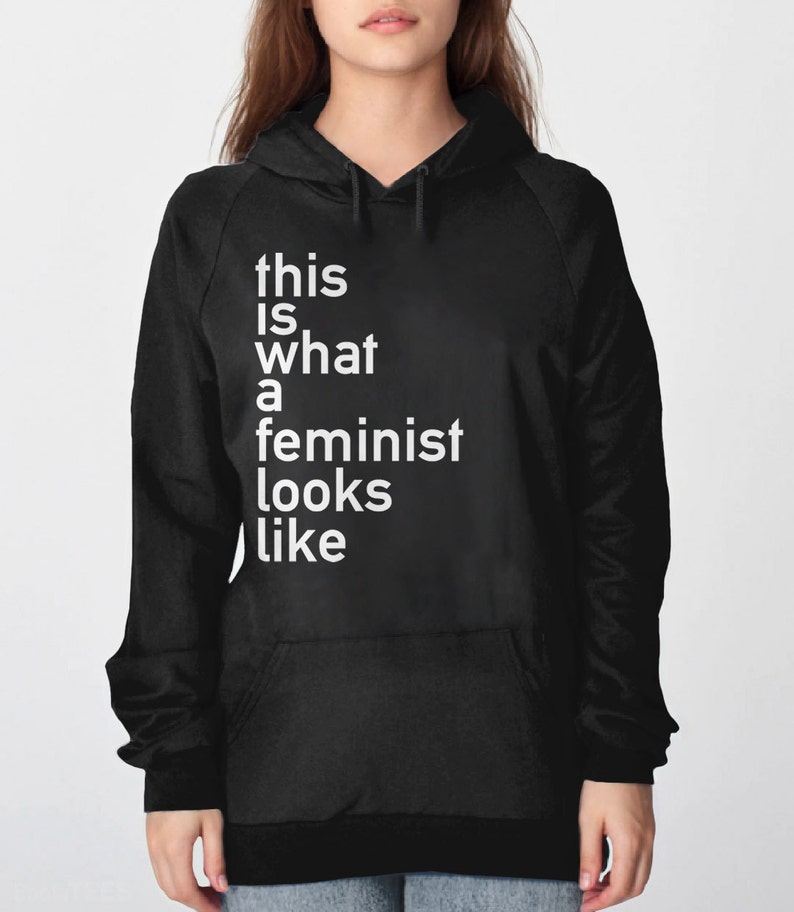 Pu&ograve; includere: Felpa con cappuccio nera con il testo "this is what a feminist looks like" in bianco.