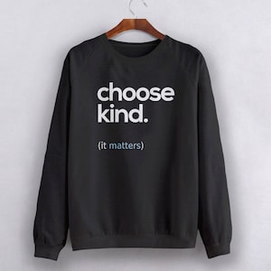 以下が含まれることがあります： 白い文字で「choose kind. (it matters)」とプリントされた黒いスウェットシャツ