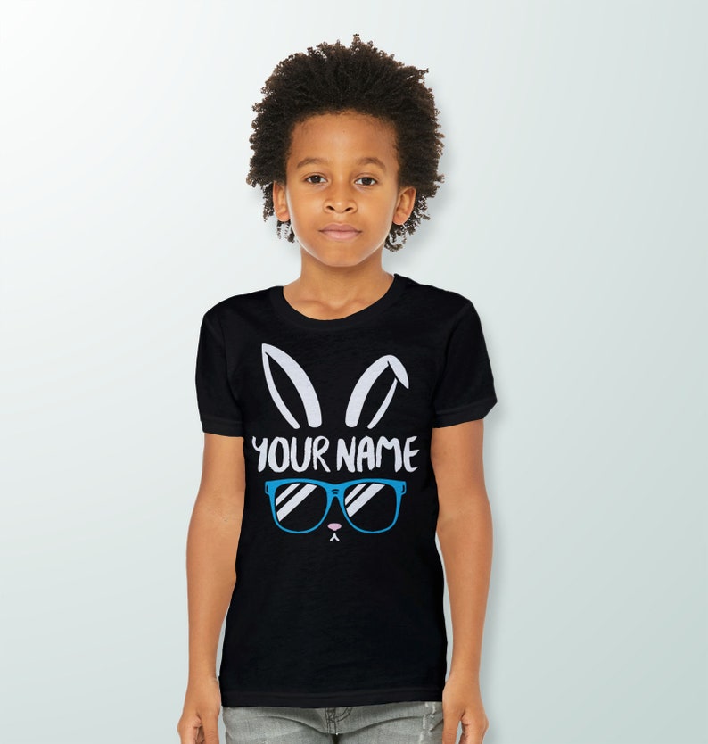 May include: Black t-shirt with a white bunny rabbit graphic wearing blue sunglasses. The text "YOUR NAME" is printed below the bunny.
