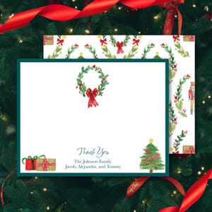 Könnte beinhalten: Eine weiße, rechteckige Grußkarte mit dunkelgrünem Rand, verziert mit einem Aquarell-Weihnachtskranz oben, einem grünen Weihnachtsbaum unten rechts und zwei Geschenken unten links. Der Text lautet Thank You The Johnson Family Jacob, Alejandra, and Tommy.