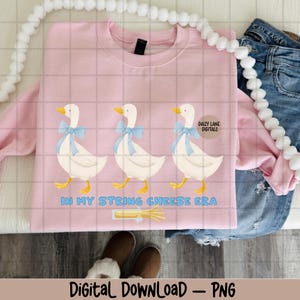 May include: A pale pink sweatshirt with a design of three white geese wearing blue bows. The text "IN MY STRING CHEESE ERA" is below the geese. The sweatshirt is a digital download.
