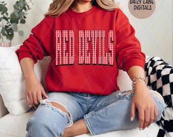 Op de afbeelding: Een rode sweatshirt met de tekst "RED DEVILS" in een vet, geblokt patroon. De tekst "Digital Download - PNG" en de merknaam "DAIZY LANE DIGITALS" zijn ook zichtbaar. De sweatshirt is rood.