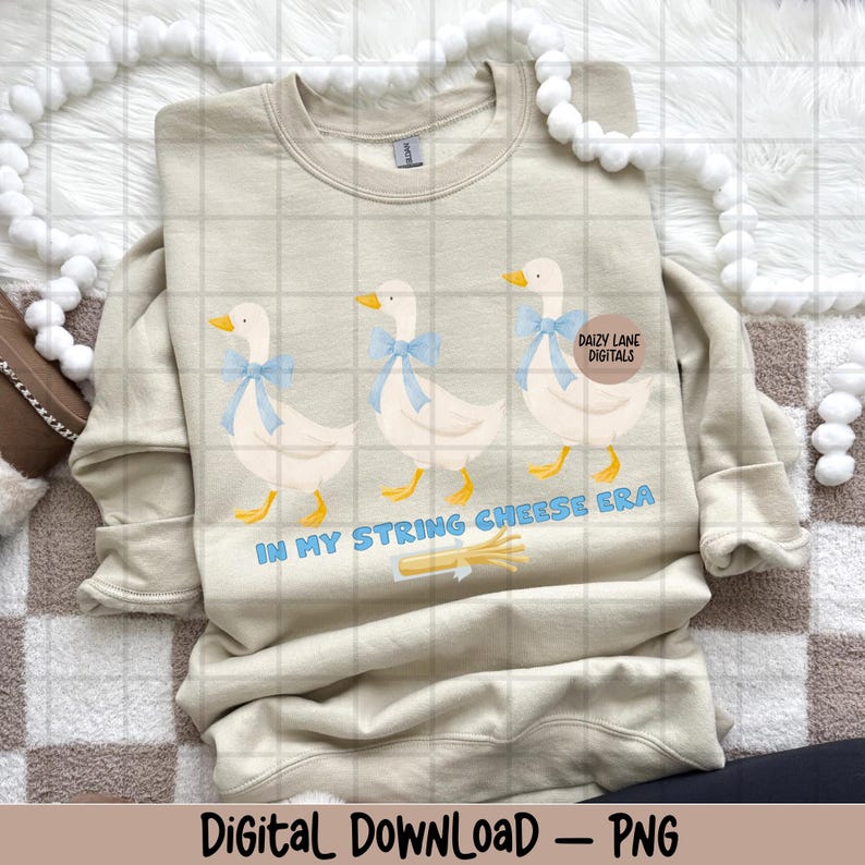 May include: A beige sweatshirt with a design of three cartoon geese wearing blue bows. The text "IN MY STRING CHEESE ERA" is below the geese. The words "Daizy Lane Digitals" are on a circular sticker on the sweatshirt.