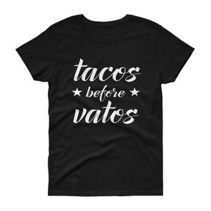 May include: Black t-shirt with white text that reads "tacos before vatos" with two white stars on either side of the word "before".