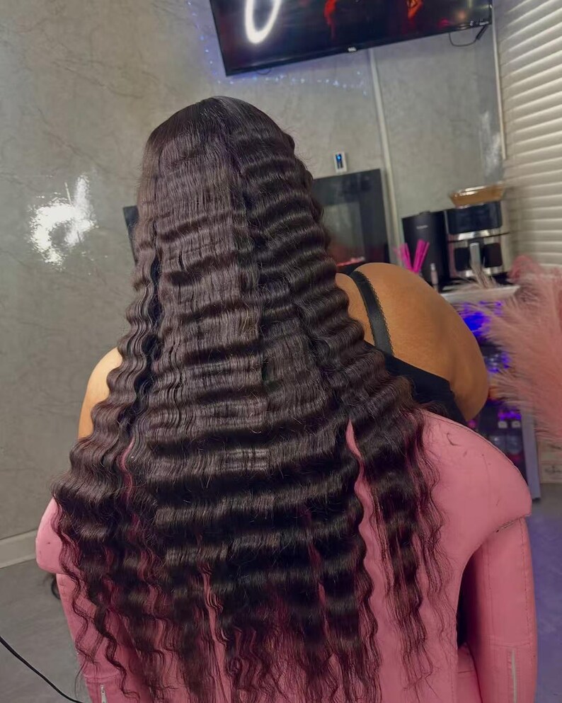 May include: Dark brown crimped hair extensions with a wavy texture. The hair is long and falls down the back. The ends of the hair have a reddish tint. The person is sitting in a pink chair.