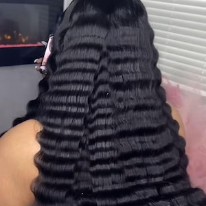May include: A close-up of long, black wavy hair. The hair has a crimped texture, creating a series of horizontal waves. The ends of the hair have a pink hue. The image is well-lit, highlighting the texture and colour of the hair.