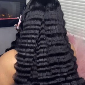 May include: A close-up of long, black wavy hair. The hair has a crimped texture, creating a series of horizontal waves. The ends of the hair have a pink hue. The image is well-lit, highlighting the texture and colour of the hair.