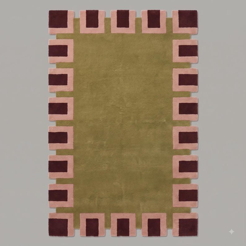 Pu&ograve; includere: Un tappeto rettangolare con un campo centrale color verde oliva a tinta unita. Il bordo presenta un motivo ripetitivo di rettangoli bordeaux scuro incorniciati da quadrati rosa chiaro, creando un profilo geometrico dentellato.