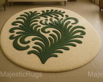 Può includere: Un tappeto rotondo beige con un grande motivo floreale verde simmetrico al centro. Il tappeto è posizionato su un pavimento piastrellato in un soggiorno, con un divano e un tavolino sullo sfondo.