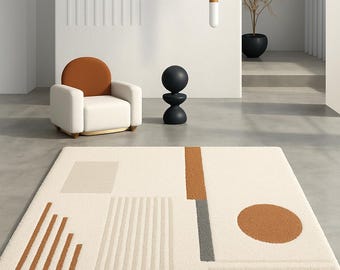 Puede incluir: Alfombra geométrica color crema con formas marrones, grises y beige. La alfombra presenta un gran círculo marrón, un rectángulo vertical marrón y gris, y varios diseños lineales y cuadrados. Un elemento de diseño de interiores moderno.