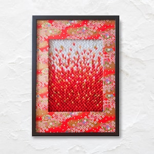 Pode incluir: Obra de arte emoldurada com uma borda preta. A obra apresenta um gradiente de elementos de papel vermelho, laranja e branco, criando um efeito texturizado e tridimensional. A moldura tem um padrão floral vermelho.