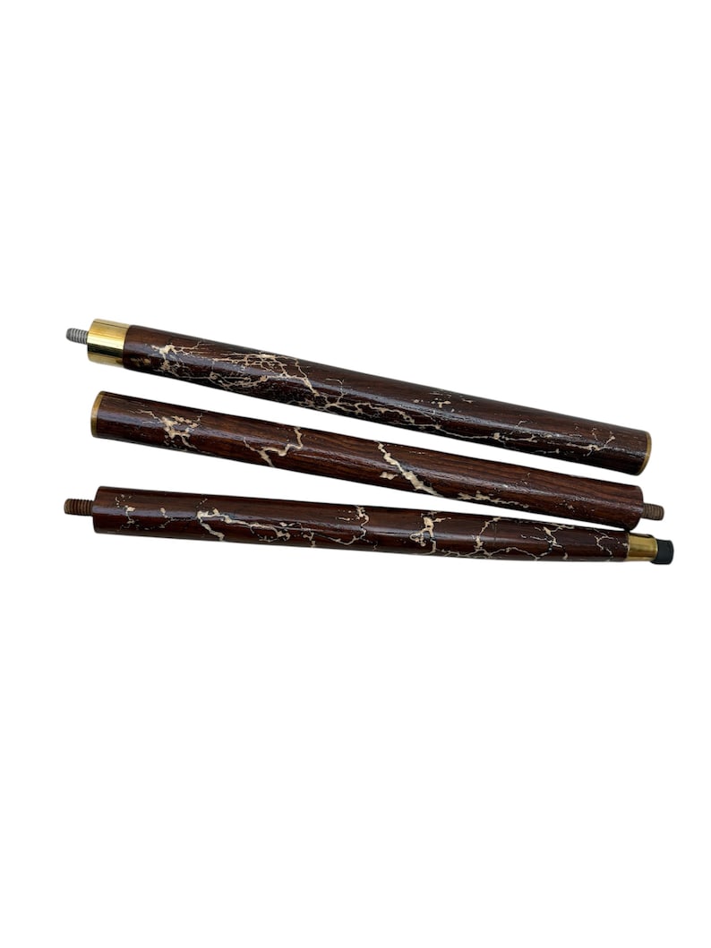 May include: Three-piece wooden cane shaft with a dark brown finish and a marbled, light-colored pattern. The cane sections have brass-colored metal accents and threaded ends for assembly. The cane is designed for mobility and support.