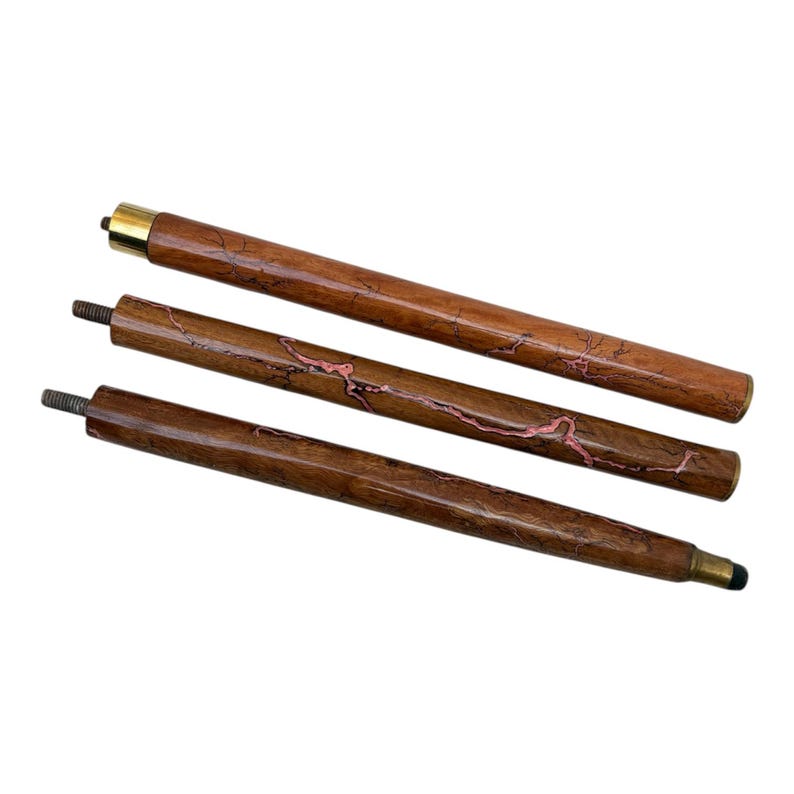 May include: Three-piece wooden walking cane with a brass tip and accents. The cane has a dark brown finish with pink veining. The top piece has a brass cap. The bottom piece has a black rubber tip.